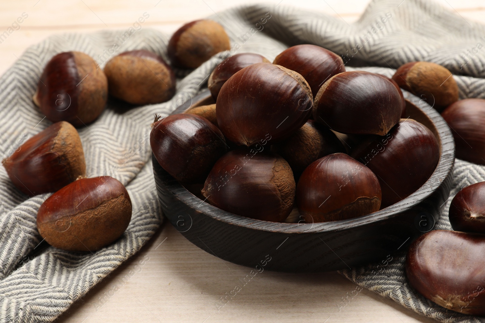 Photo of Sweet fresh edible chestnuts on light wooden table, closeup