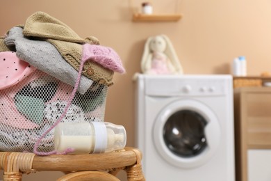 Laundry basket with baby clothes on stool in bathroom, space for text