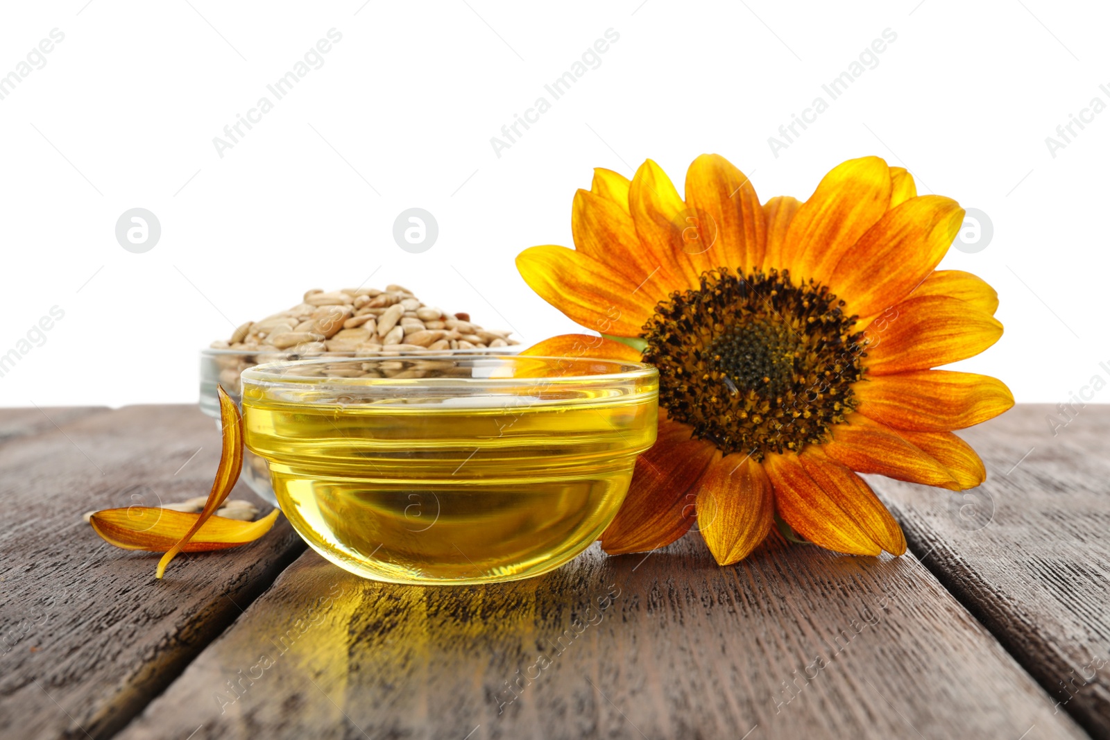 Photo of Sunflower, oil and seeds on wooden table against white background