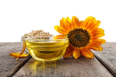 Photo of Sunflower, oil and seeds on wooden table against white background