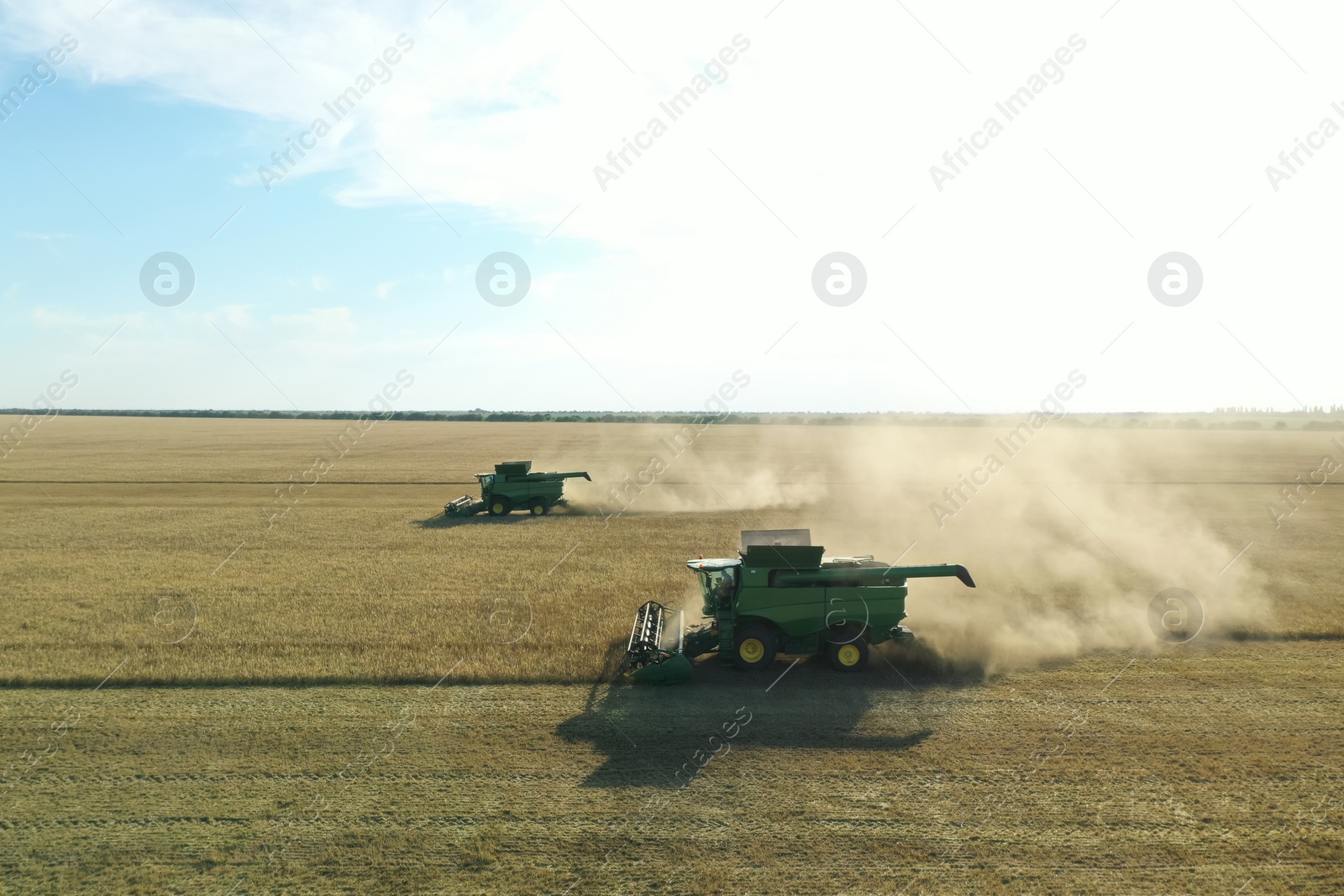 Photo of Beautiful aerial view of modern combine harvesters working in field on sunny day. Agriculture industry