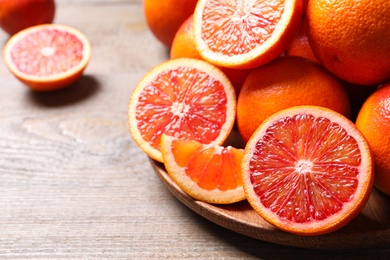 Whole and cut red oranges on wooden table, closeup