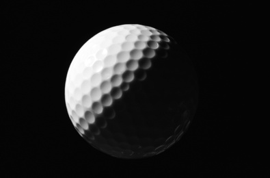 Photo of New white golf ball against dark background