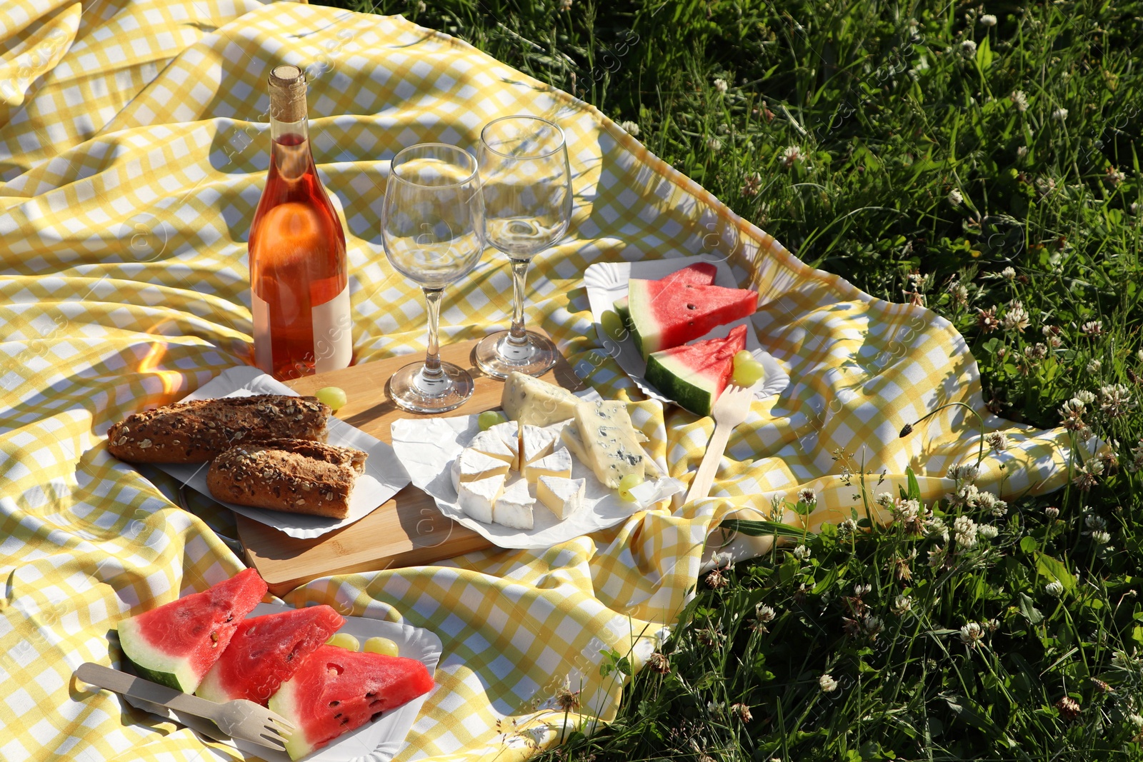 Photo of Picnic blanket with delicious food and wine on green grass outdoors