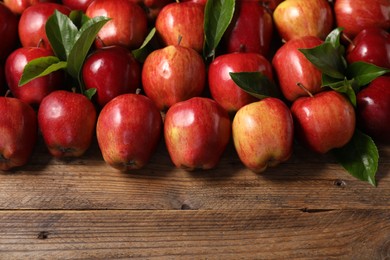 Photo of Fresh ripe red apples and leaves on wooden table. Space for text