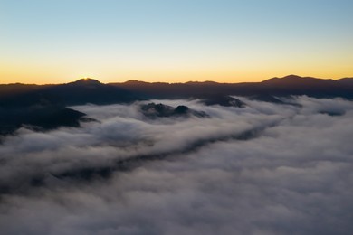 Image of Beautiful landscape with thick mist in mountains at sunset. Drone photography