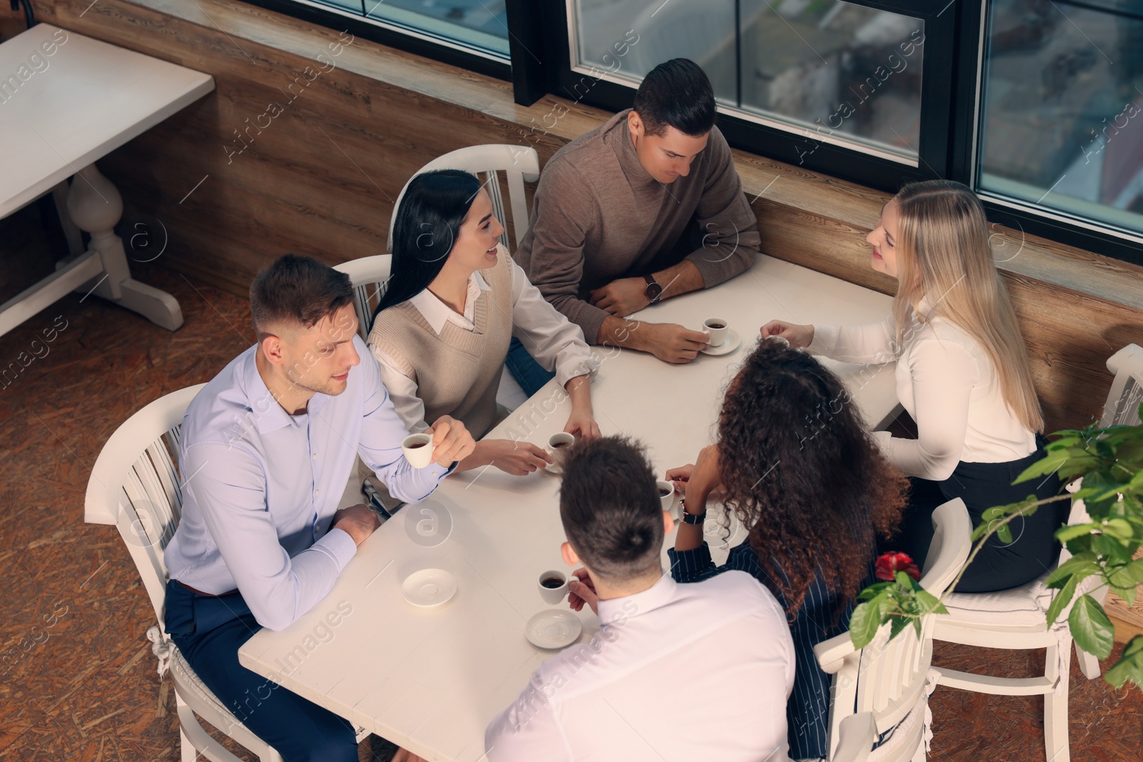 Photo of Group of coworkers having coffee break in cafe, above view