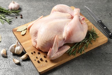Photo of Fresh raw chicken with spices and knife on grey textured table