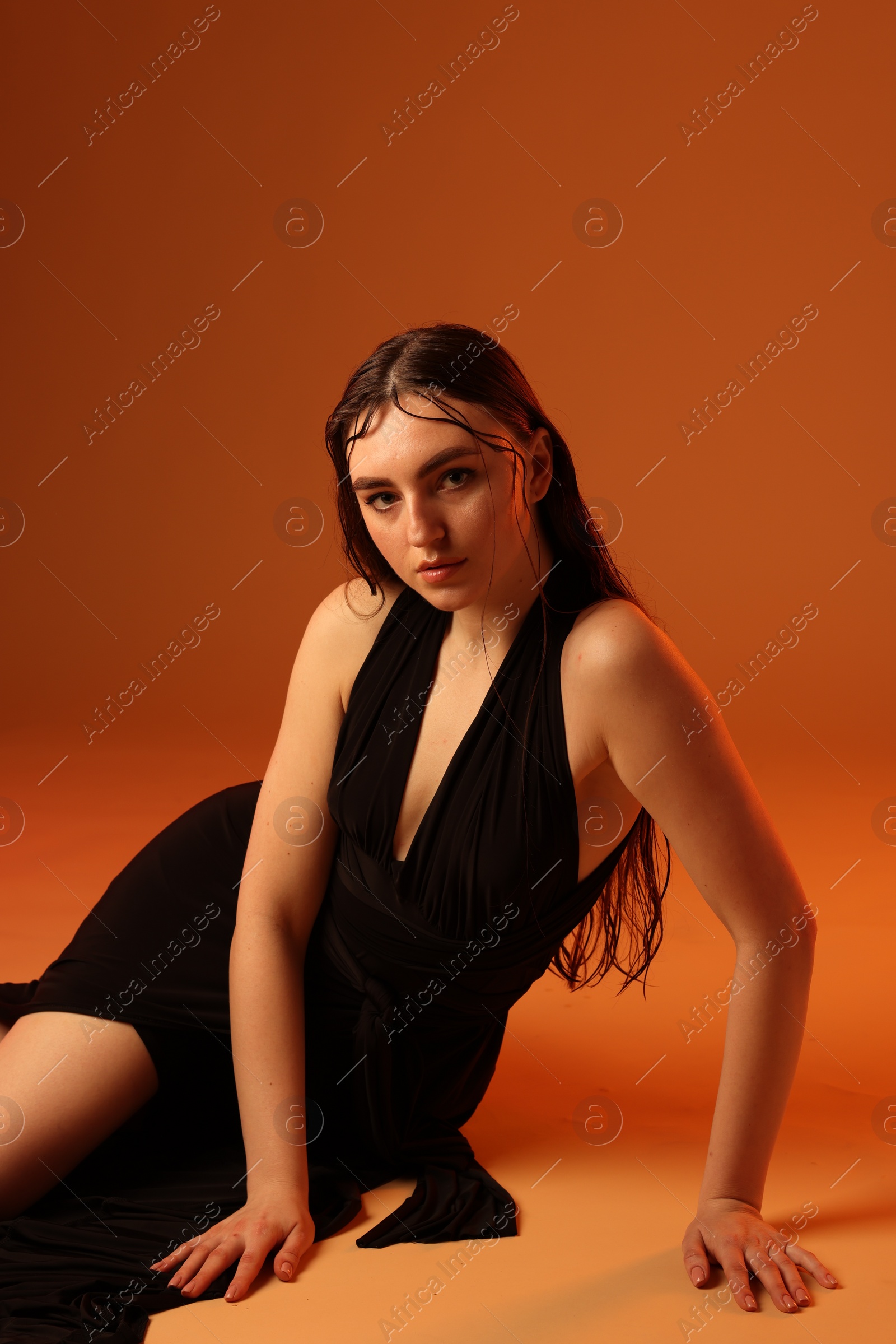 Photo of Beautiful woman in black dress posing on brown background