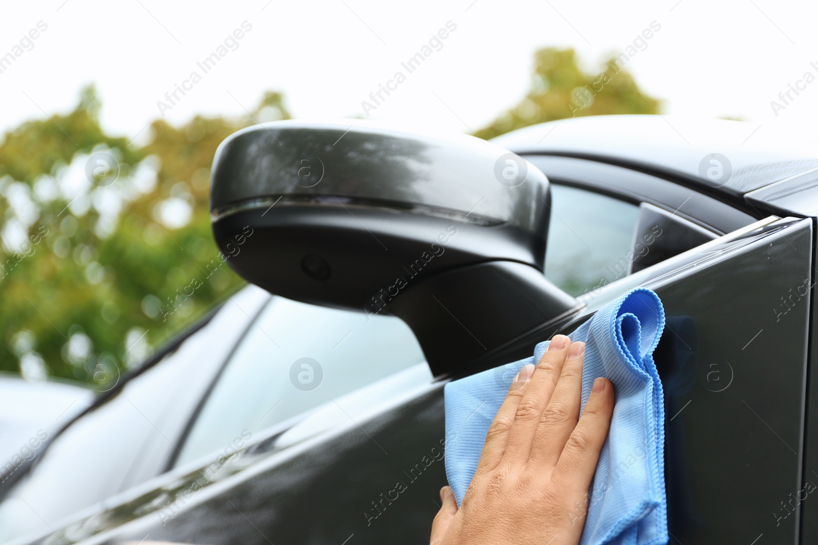 Photo of Man washing car door with rag outdoors, closeup