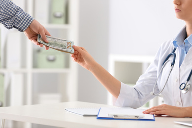 Patient giving bribe to doctor in clinic, closeup. Corrupted medicine