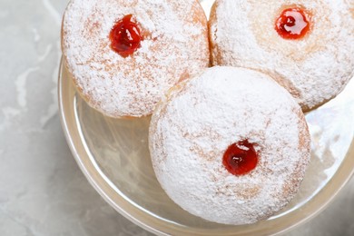 Photo of Delicious donuts with jelly and powdered sugar on pastry stand, closeup