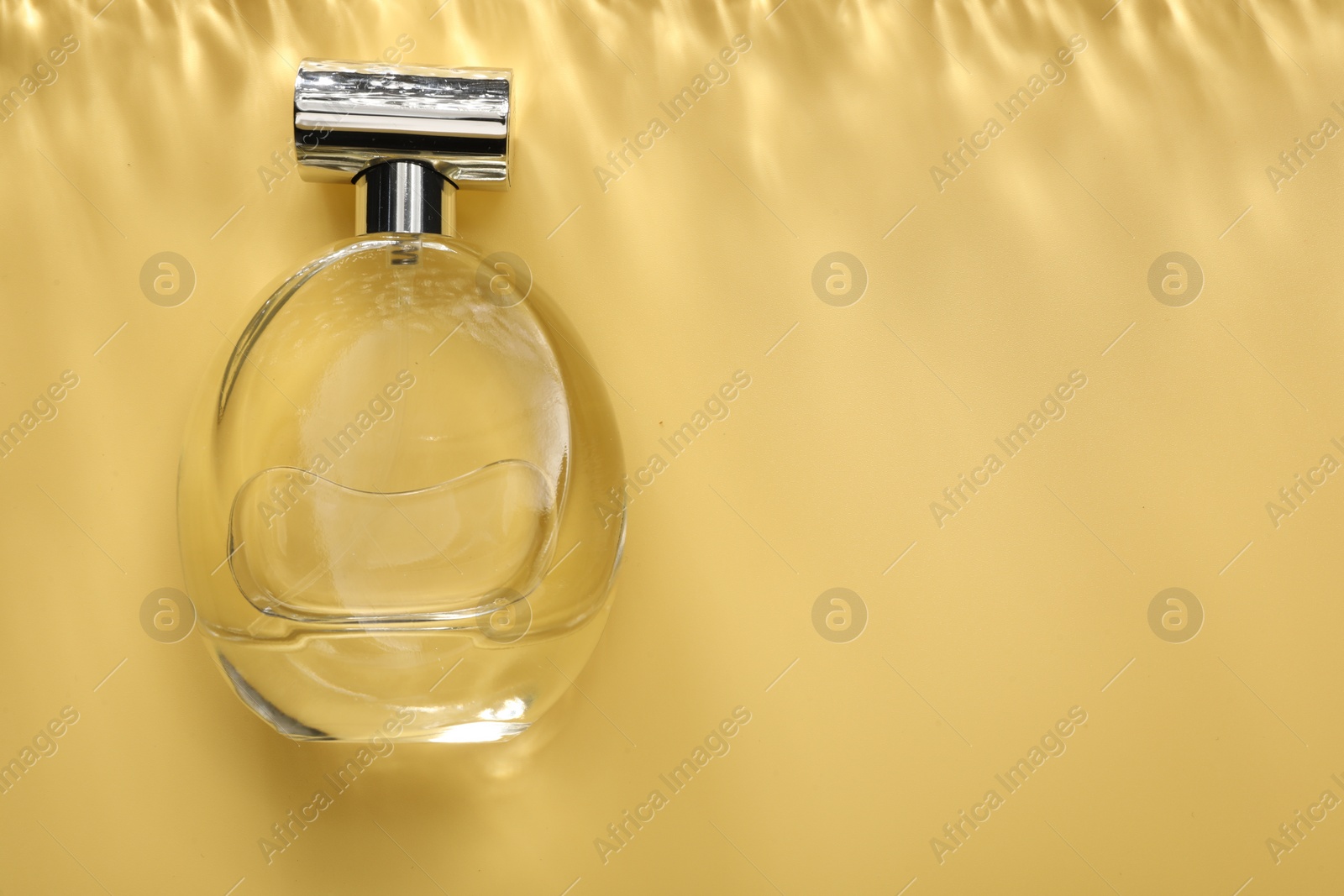 Photo of Perfume in bottle on golden background, top view. Space for text
