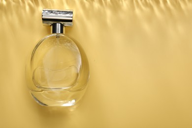 Perfume in bottle on golden background, top view. Space for text