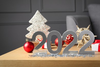 Photo of Silver number 2022 and festive decor on wooden table indoors. Happy New Year