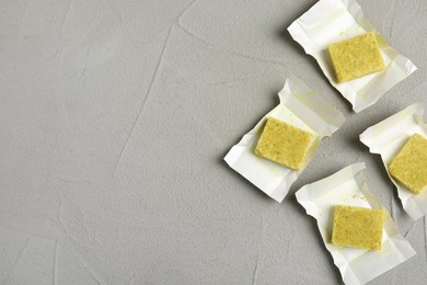 Photo of Bouillon cubes with wraps on light grey table, flat lay. Space for text