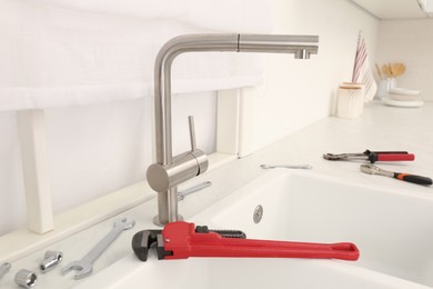 Photo of Installed water tap and plumber's tools near sink on countertop in kitchen