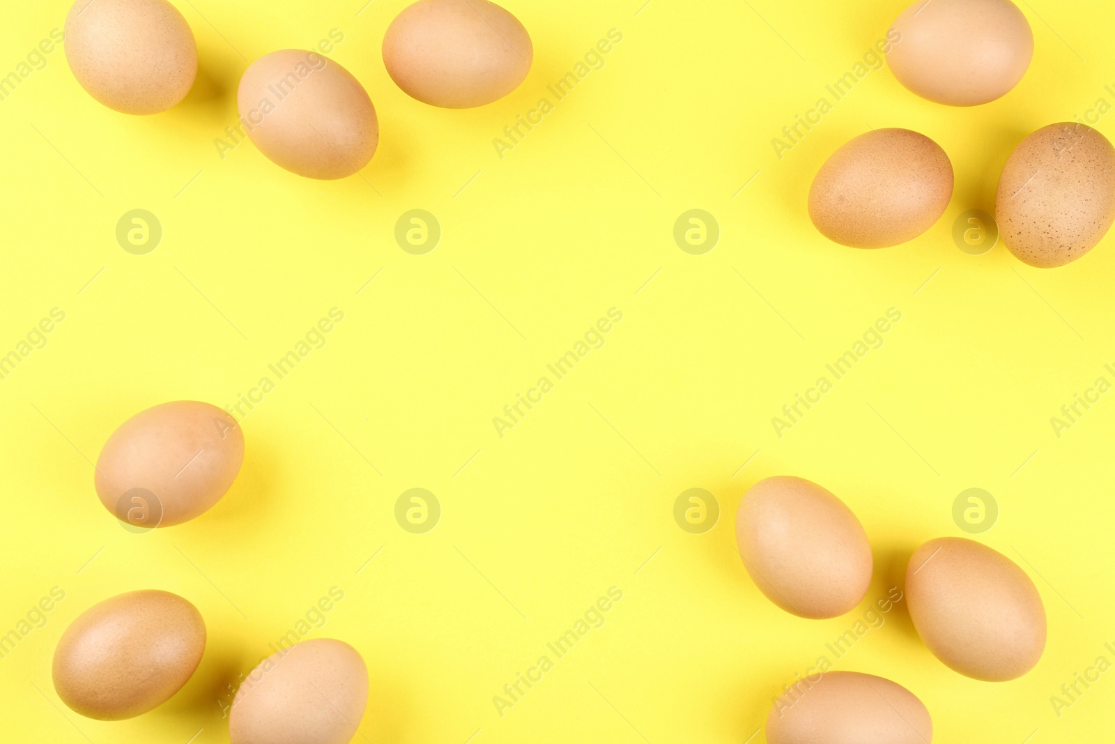 Photo of Raw chicken eggs on yellow background, flat lay. Space for text