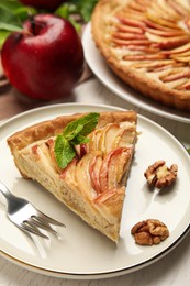 Slice of delicious apple pie on white wooden table