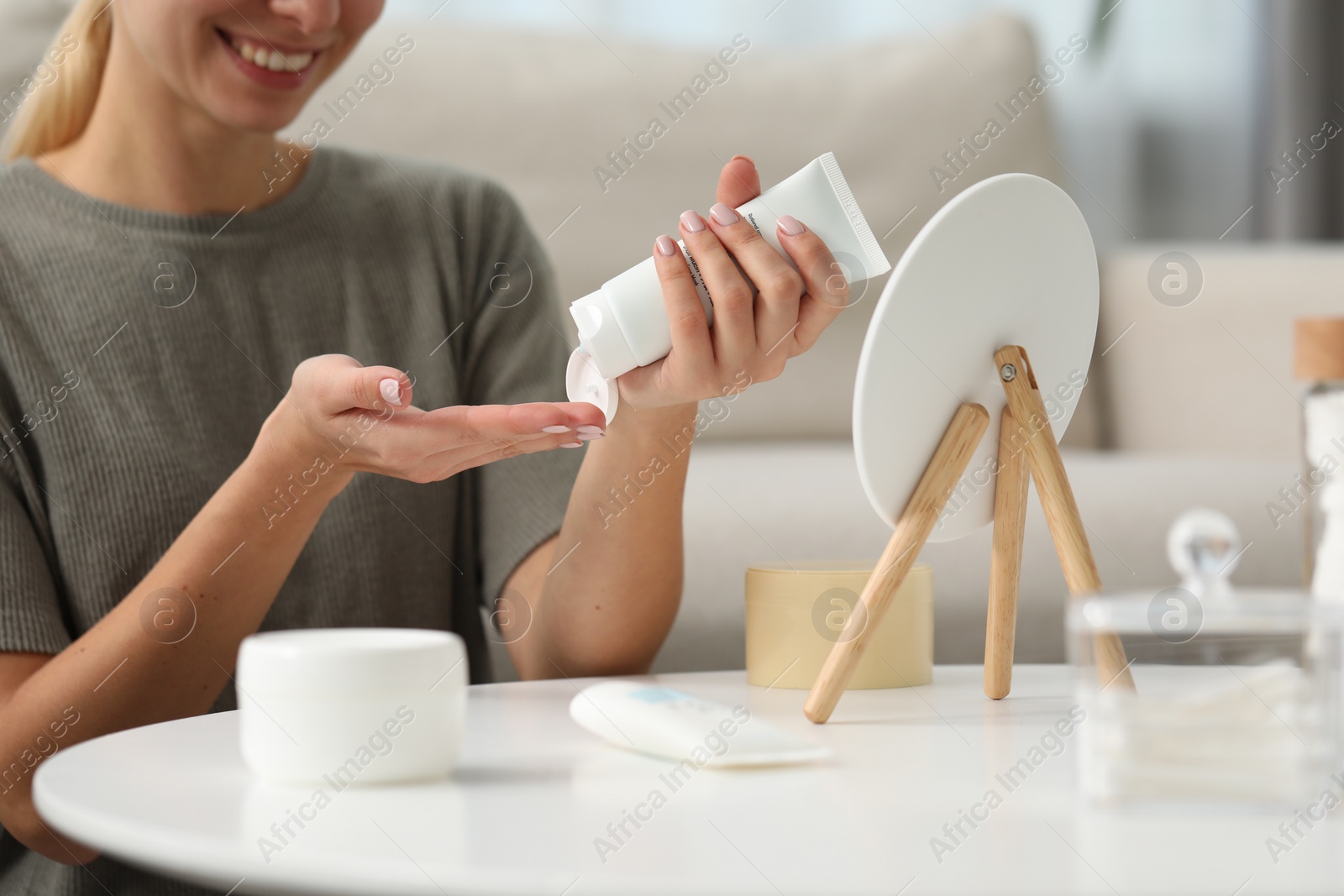 Photo of Young woman applying cream onto hand at home closeup. Spa treatments