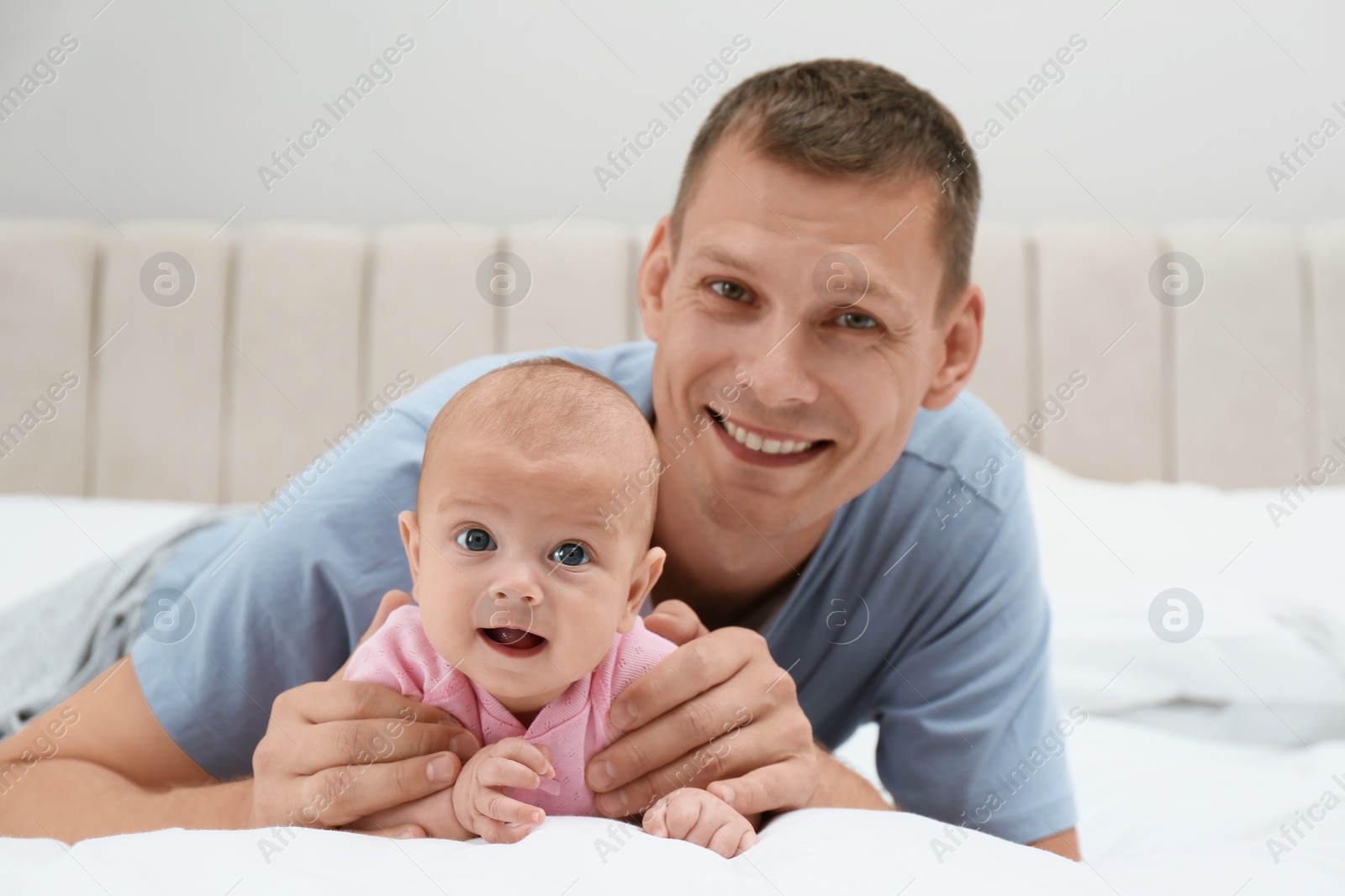 Photo of Happy father with his cute baby on bed at home