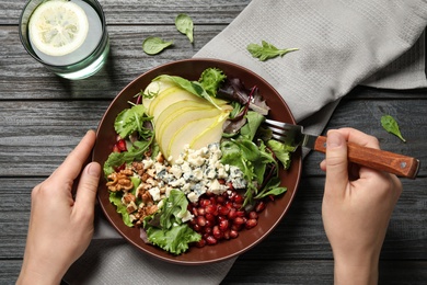 Woman with tasty pear salad at black wooden table, top view