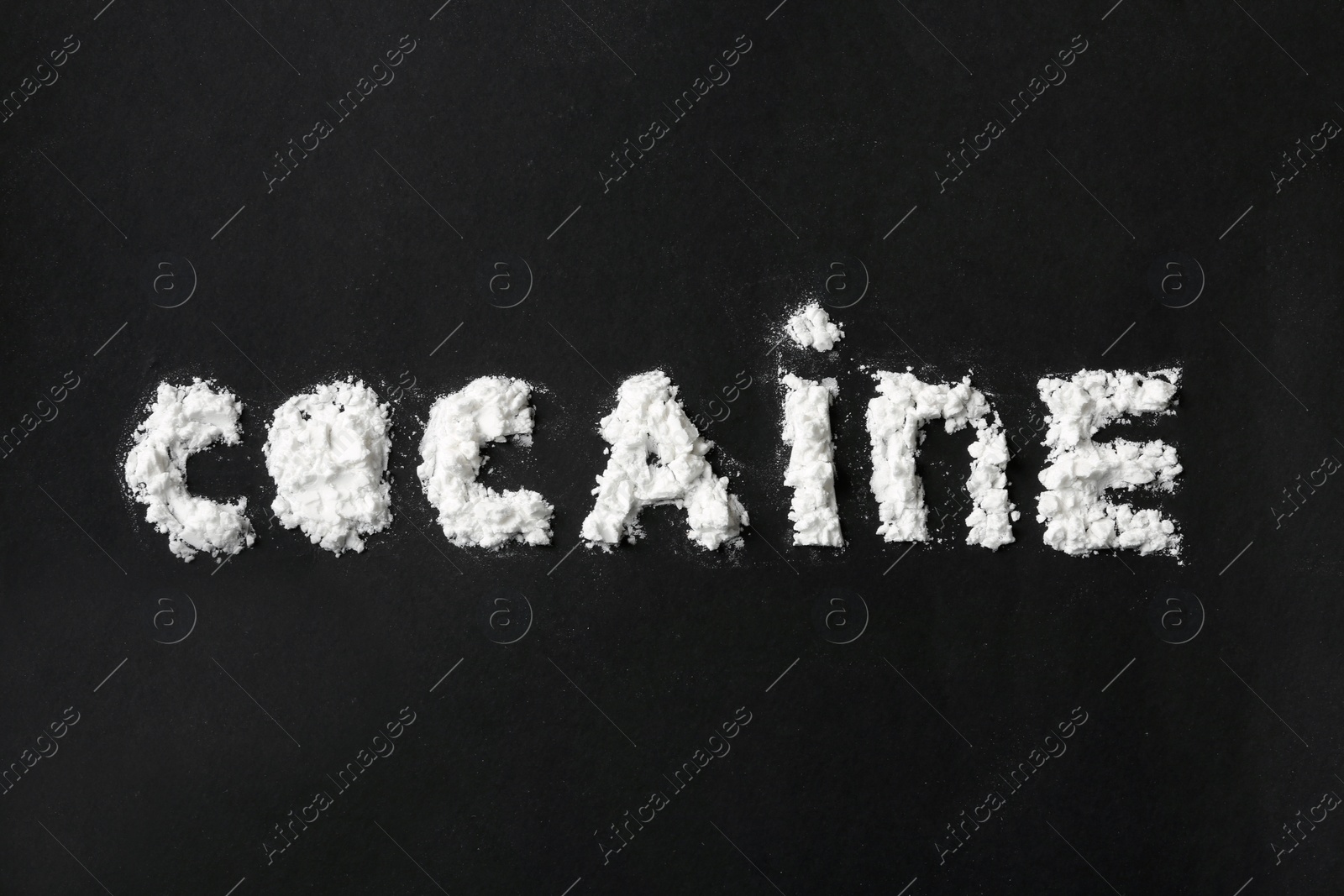 Photo of Word Cocaine written with white powder on black background, top view