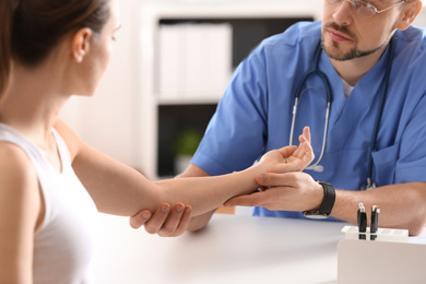 Photo of Male orthopedist examining patient's arm in clinic, closeup