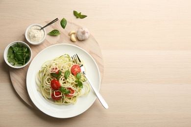 Tasty zucchini pasta with tomatoes and basil served on wooden table, flat lay. Space for text