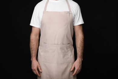 Photo of Man wearing kitchen apron on black background, closeup. Mockup for design