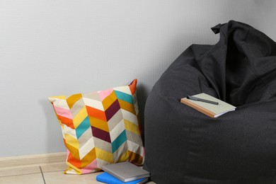 Photo of Black cozy bean bag chair near light grey wall in room