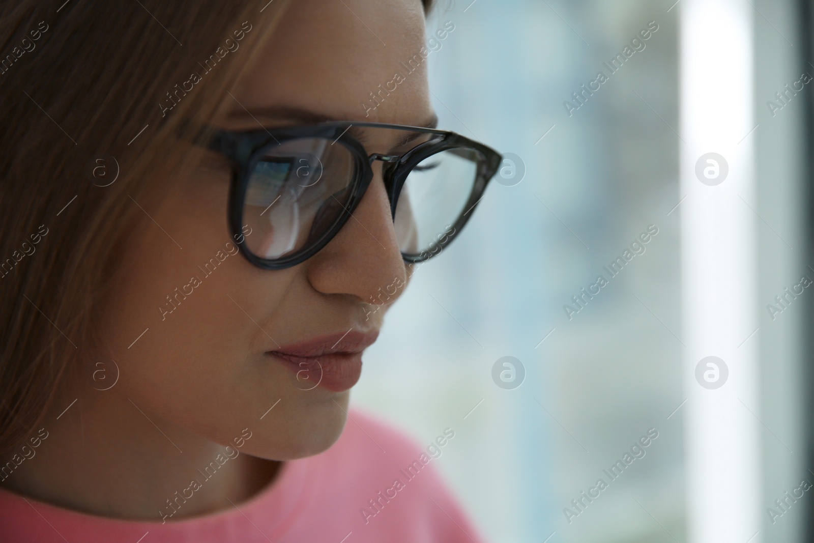 Photo of Young woman wearing glasses on blurred background, closeup. Ophthalmology service