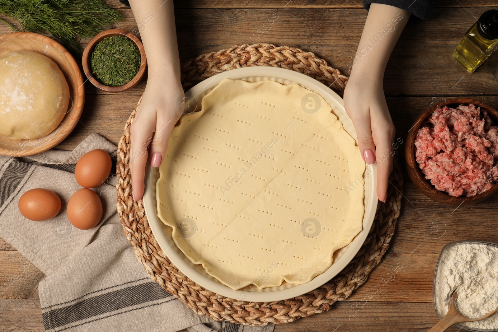 Photo of Woman making meat pie at wooden table, top view