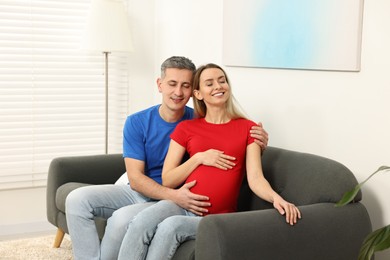 Young family housing concept. Pregnant woman with her husband on sofa at home
