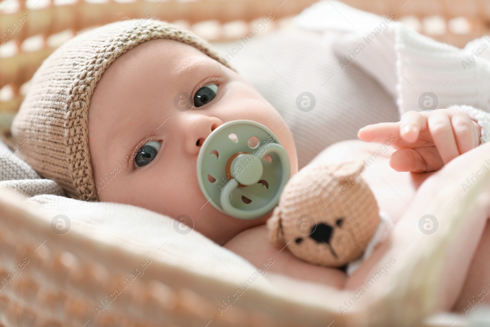 Photo of Cute newborn baby on white blanket in wicker crib, closeup