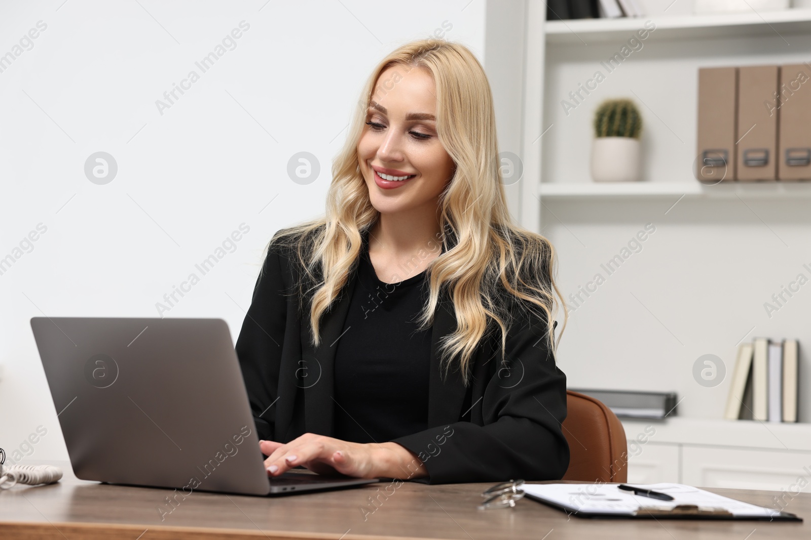 Photo of Happy secretary working with laptop in office