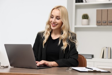 Photo of Happy secretary working with laptop in office