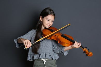 Preteen girl playing violin on black background