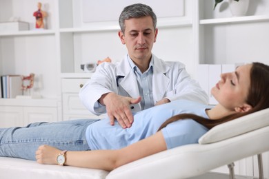 Photo of Gastroenterologist examining patient with stomach pain on couch in clinic