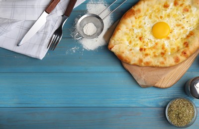 Photo of Fresh homemade khachapuri with cheese and egg served on light blue wooden table, flat lay. Space for text