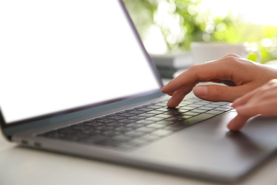 Woman working with modern laptop at white wooden table, closeup