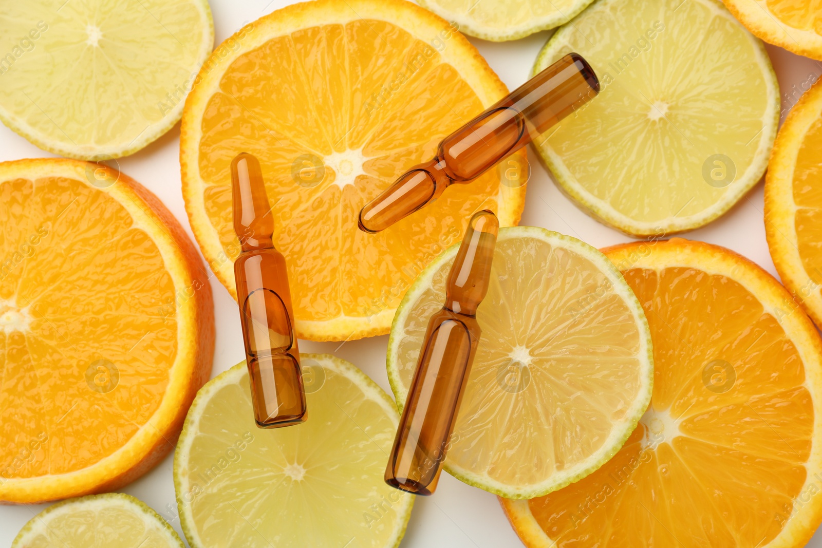 Photo of Skincare ampoules with vitamin C, lemon and orange slices on white background, flat lay