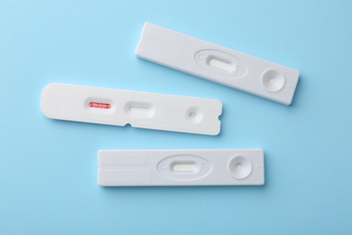Different disposable express tests on light blue background, flat lay
