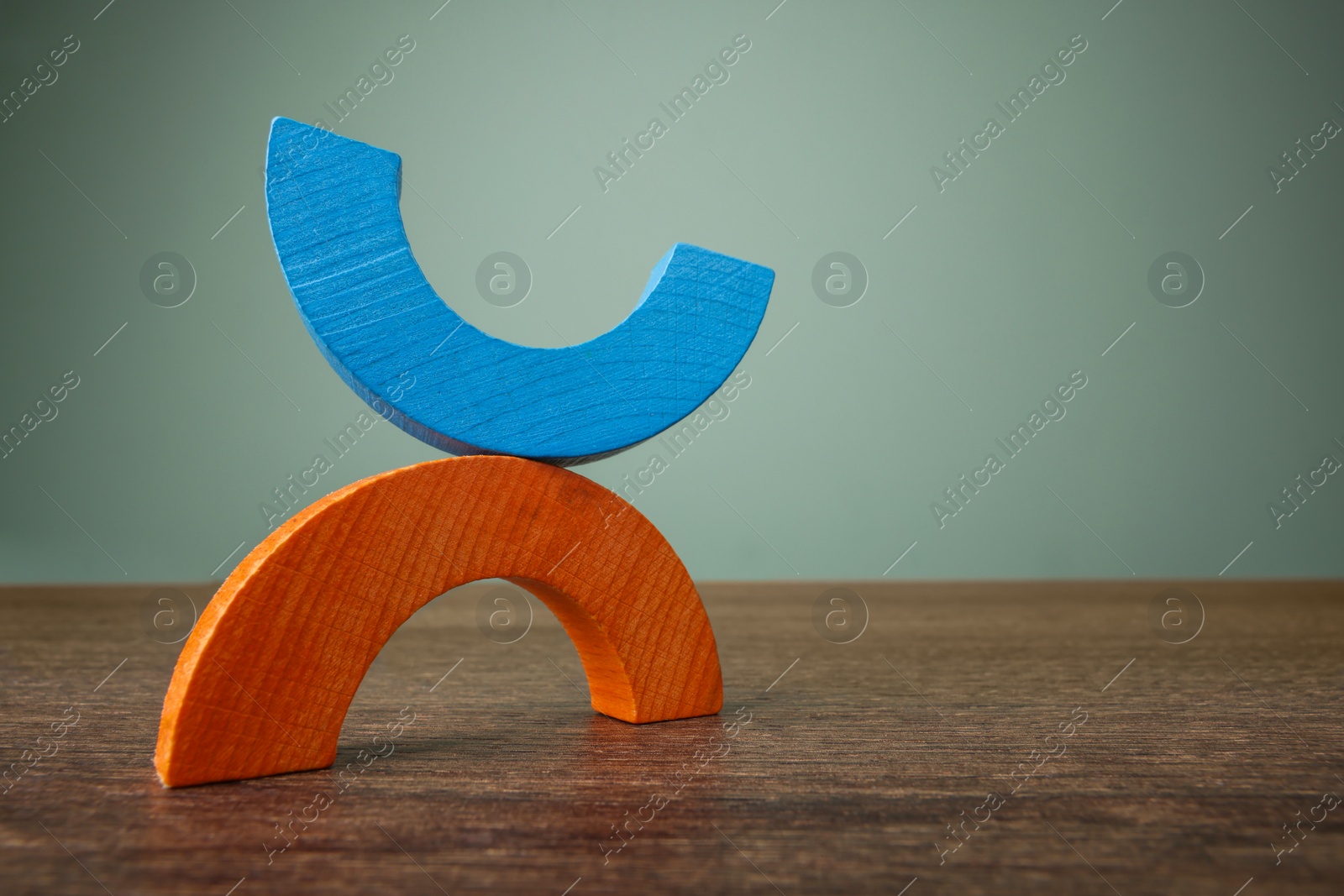 Photo of Colorful wooden pieces of educational toy on table against grey wall, low angle view and space for text. Motor skills development