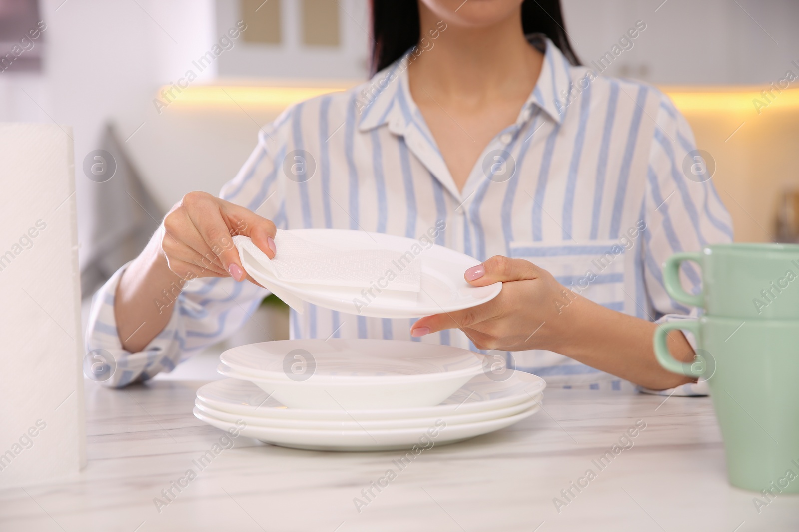 Photo of Woman wiping plate with paper towel in kitchen, closeup