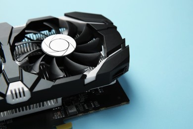 Photo of Computer graphics card on light blue background, closeup. Space for text