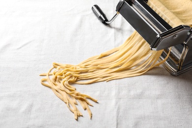 Pasta maker with wheat dough on light background