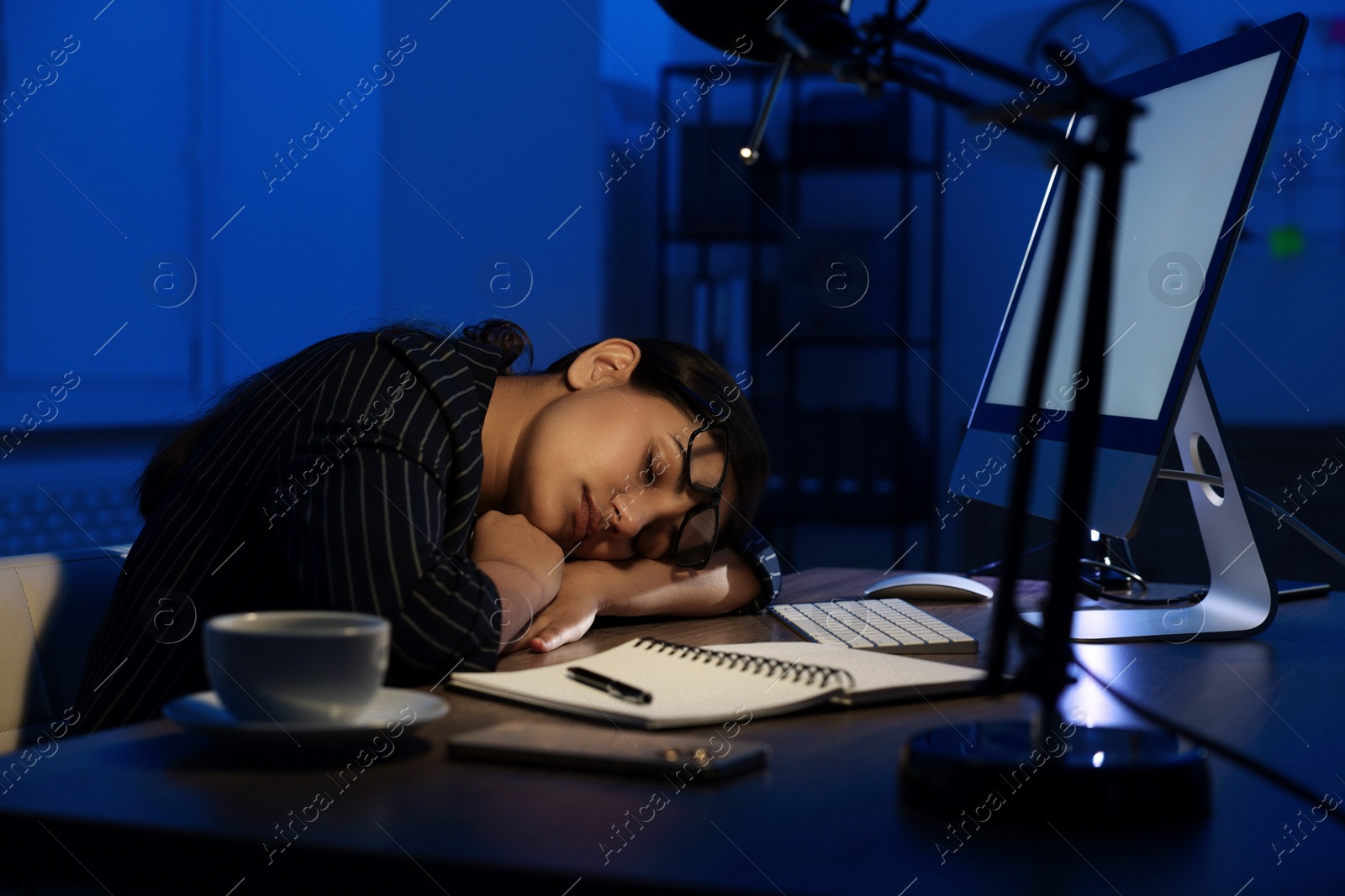 Photo of Tired overworked businesswoman napping at night in office