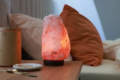 Photo of Himalayan salt lamp, air ionizer and accessories on nightstand in bedroom