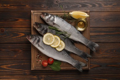 Sea bass fish and ingredients on wooden table, top view